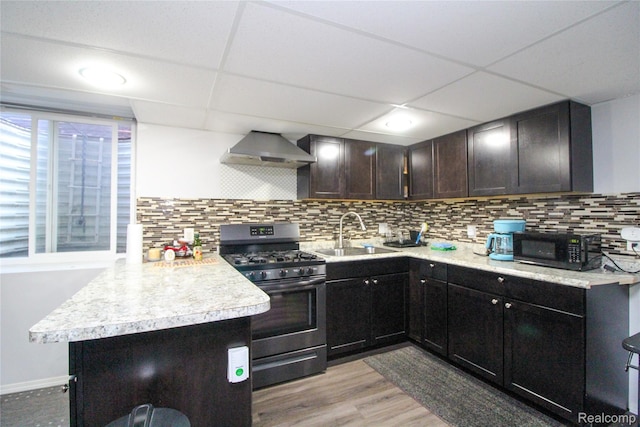 30475 Berghway Trl, Warren, MI 48092 - kitchen featuring gas range, black microwave, wall chimney range hood, a peninsula, and light countertops