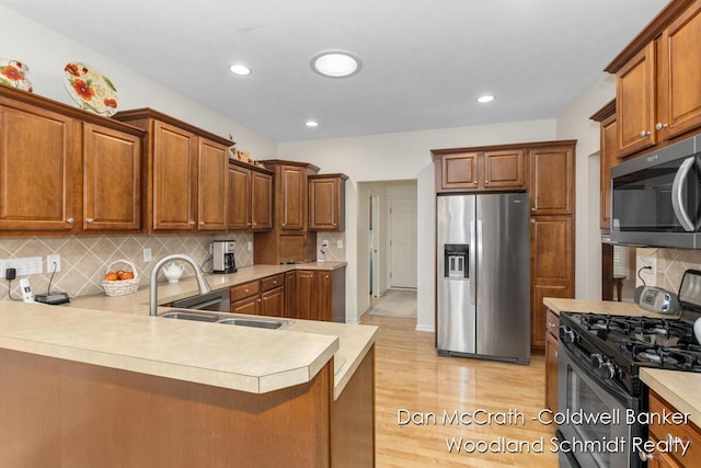1809 Woodside Trl NW, Grand Rapids, MI 49504 - kitchen with stainless steel appliances, light countertops, light wood-style flooring, tasteful backsplash, and brown cabinetry