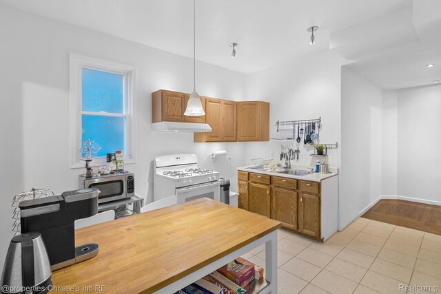 4751 Trumbull St, Detroit, MI 48208 - kitchen featuring white gas stove, under cabinet range hood, stainless steel microwave, light countertops, and decorative light fixtures