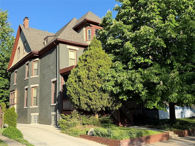 4751 Trumbull St, Detroit, MI 48208 - view of side of property with a chimney, brick siding, and a shingled roof