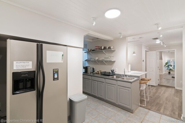 4751 Trumbull St, Detroit, MI 48208 - kitchen with fridge with ice dispenser, a kitchen bar, open shelves, crown molding, and gray cabinets