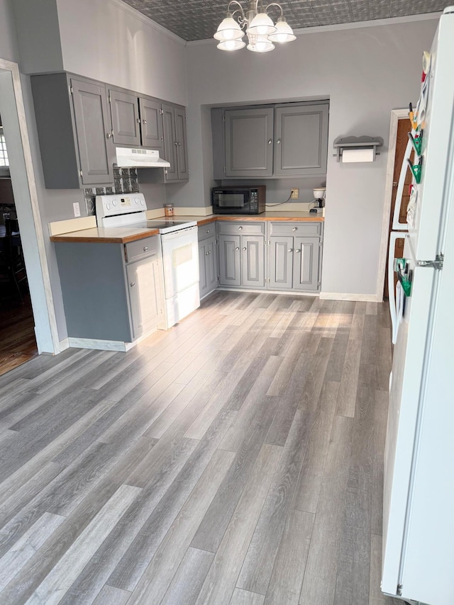 423 E Prairie St, Vicksburg, MI 49097 - kitchen featuring white appliances, gray cabinets, under cabinet range hood, a chandelier, and light wood-type flooring