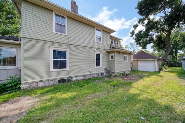 1302 Lansing Ave, Jackson, MI 49202 - rear view of house with a chimney, a detached garage, and a yard