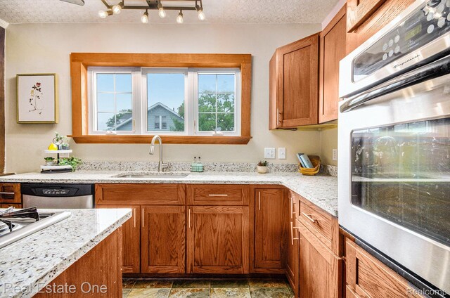 22500 Boulder Ave, Eastpointe, MI 48021 - kitchen featuring appliances with stainless steel finishes, a textured ceiling, brown cabinetry, light stone counters, and light stone finish floors