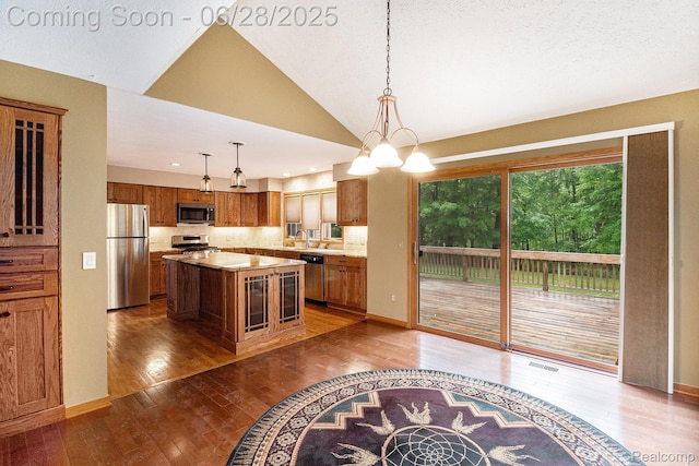 6375 Perryville Rd, Holly, MI 48442 - kitchen featuring stainless steel appliances, brown cabinetry, hardwood / wood-style flooring, light countertops, and a kitchen island