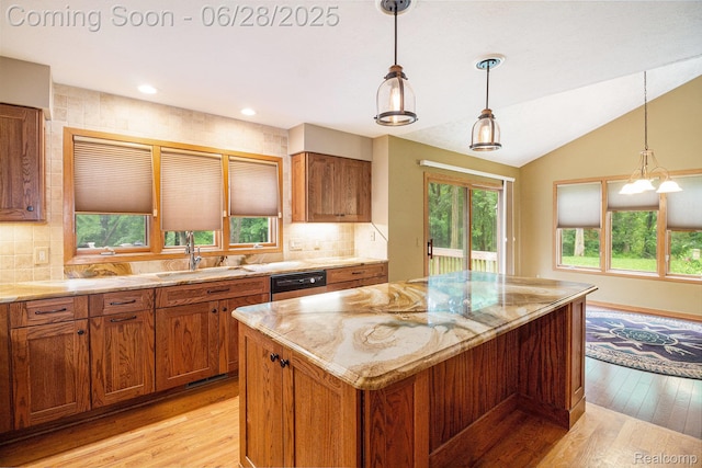 6375 Perryville Rd, Holly, MI 48442 - kitchen featuring light wood-style flooring, brown cabinetry, light stone counters, vaulted ceiling, and a kitchen island