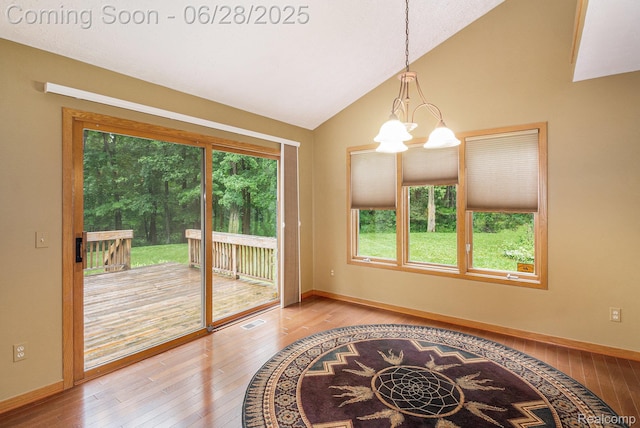 6375 Perryville Rd, Holly, MI 48442 - unfurnished dining area featuring lofted ceiling, plenty of natural light, wood-type flooring, and a chandelier