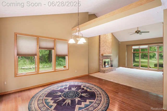 6375 Perryville Rd, Holly, MI 48442 - unfurnished living room featuring vaulted ceiling, ceiling fan, a brick fireplace, wood-type flooring, and a chandelier