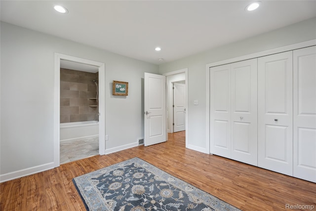 3395 W Maple Rd, Wixom, MI 48393 - unfurnished bedroom featuring wood finished floors, ensuite bathroom, recessed lighting, and a closet
