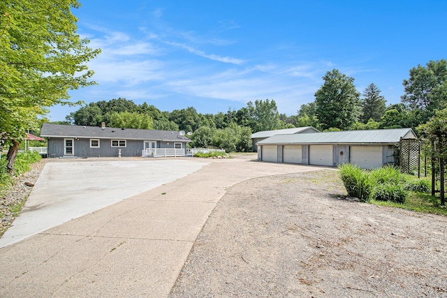 11303 W Dr N, Bellevue, MI 49021 - ranch-style home with a garage, driveway, view of wooded area, and an outbuilding