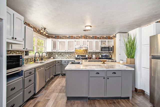 11303 W Dr N, Bellevue, MI 49021 - kitchen featuring appliances with stainless steel finishes, gray cabinetry, a kitchen island with sink, and backsplash