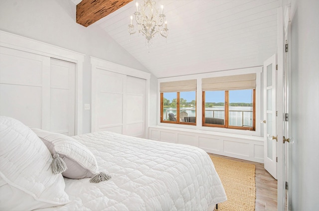 4449 Cordley Lake Rd, Pinckney, MI 48169 - bedroom featuring two closets, a chandelier, light wood-style flooring, a decorative wall, and a water view