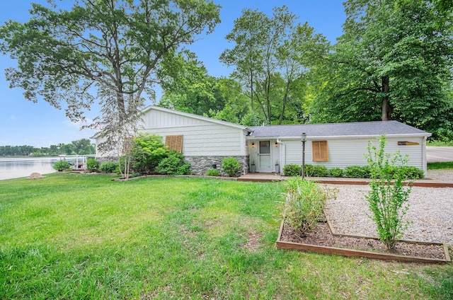 4449 Cordley Lake Rd, Pinckney, MI 48169 - view of front of house featuring a front yard, stone siding, a water view, and a vegetable garden