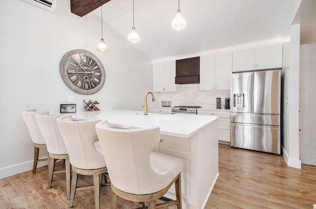 4449 Cordley Lake Rd, Pinckney, MI 48169 - kitchen with stainless steel appliances, vaulted ceiling, under cabinet range hood, decorative backsplash, and a breakfast bar area