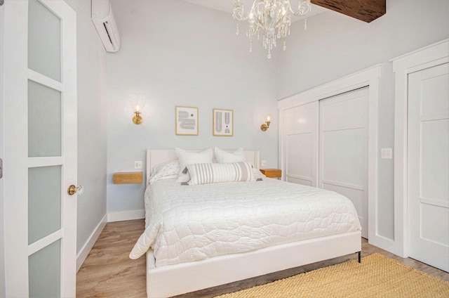 4449 Cordley Lake Rd, Pinckney, MI 48169 - bedroom featuring an AC wall unit, wood finished floors, a chandelier, a towering ceiling, and a closet