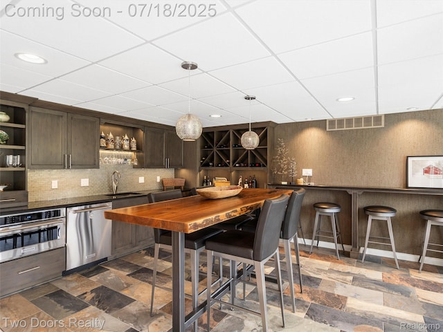 3551 Royal Berkshire Ln, Oakland, MI 48363 - kitchen with open shelves, dark countertops, a paneled ceiling, dark brown cabinets, and appliances with stainless steel finishes