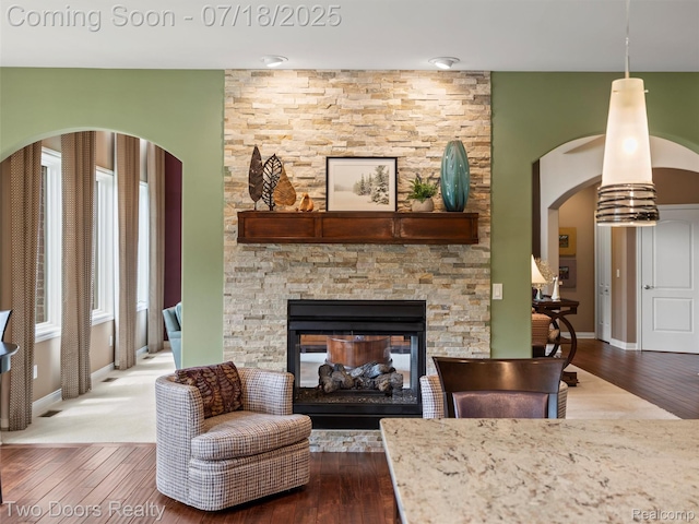 3551 Royal Berkshire Ln, Oakland, MI 48363 - living area featuring arched walkways, wood finished floors, and a stone fireplace