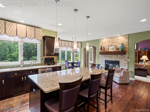3551 Royal Berkshire Ln, Oakland, MI 48363 - kitchen featuring a kitchen island, light stone countertops, dark brown cabinets, dark wood-style flooring, and recessed lighting