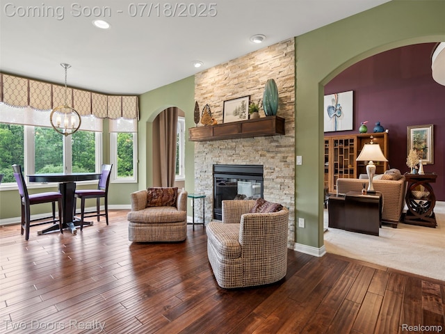 3551 Royal Berkshire Ln, Oakland, MI 48363 - living area with arched walkways, hardwood / wood-style flooring, a chandelier, and a stone fireplace