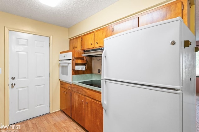 5232 Maple Ave, Swartz Creek, MI 48473 - kitchen featuring white appliances, under cabinet range hood, light wood-style flooring, a textured ceiling, and light countertops