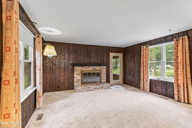 5232 Maple Ave, Swartz Creek, MI 48473 - unfurnished living room with wooden walls, healthy amount of natural light, a fireplace, and light colored carpet