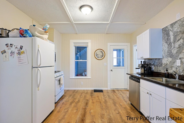 2550 Crozier Ave, Muskegon, MI 49441 - kitchen with white appliances, dark countertops, white cabinets, light wood-style floors, and a textured ceiling