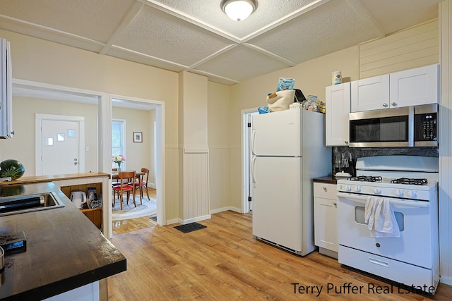 2550 Crozier Ave, Muskegon, MI 49441 - kitchen featuring white appliances, dark countertops, light wood-style flooring, white cabinets, and wainscoting
