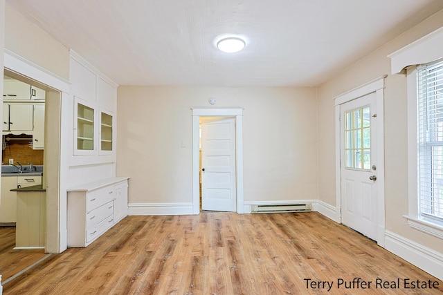 2550 Crozier Ave, Muskegon, MI 49441 - unfurnished dining area featuring a baseboard radiator, light wood-type flooring, and healthy amount of natural light