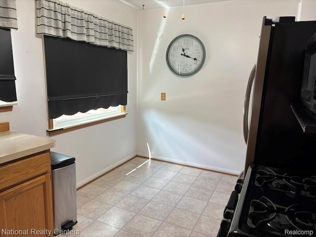 1618 E Lincoln Ave, Royal Oak, MI 48067 - kitchen with light tile patterned flooring, brown cabinetry, light countertops, freestanding refrigerator, and gas range oven