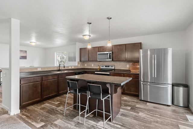 25596 Forest Ln, Mattawan, MI 49071 - kitchen with stainless steel appliances, dark countertops, a kitchen island, a breakfast bar area, and dark wood finished floors