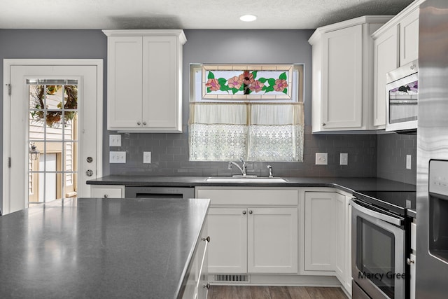 5589 Sandalwood Ct Unit 22, Norton Shores, MI 49441 - kitchen featuring stainless steel appliances, dark countertops, white cabinets, and a textured ceiling