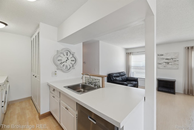 9451 Parkwood N, Davison, MI 48423 - kitchen with washer and dryer, a peninsula, light wood-type flooring, a textured ceiling, and light countertops