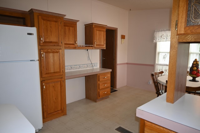 4105 Sawgrass Trl, Muskegon, MI 49442 - kitchen with freestanding refrigerator, light flooring, brown cabinetry, light countertops, and a desk