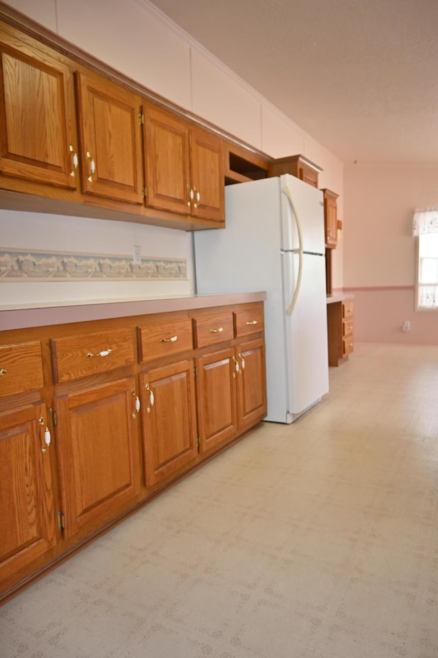 4105 Sawgrass Trl, Muskegon, MI 49442 - kitchen with brown cabinetry, freestanding refrigerator, light countertops, and light flooring