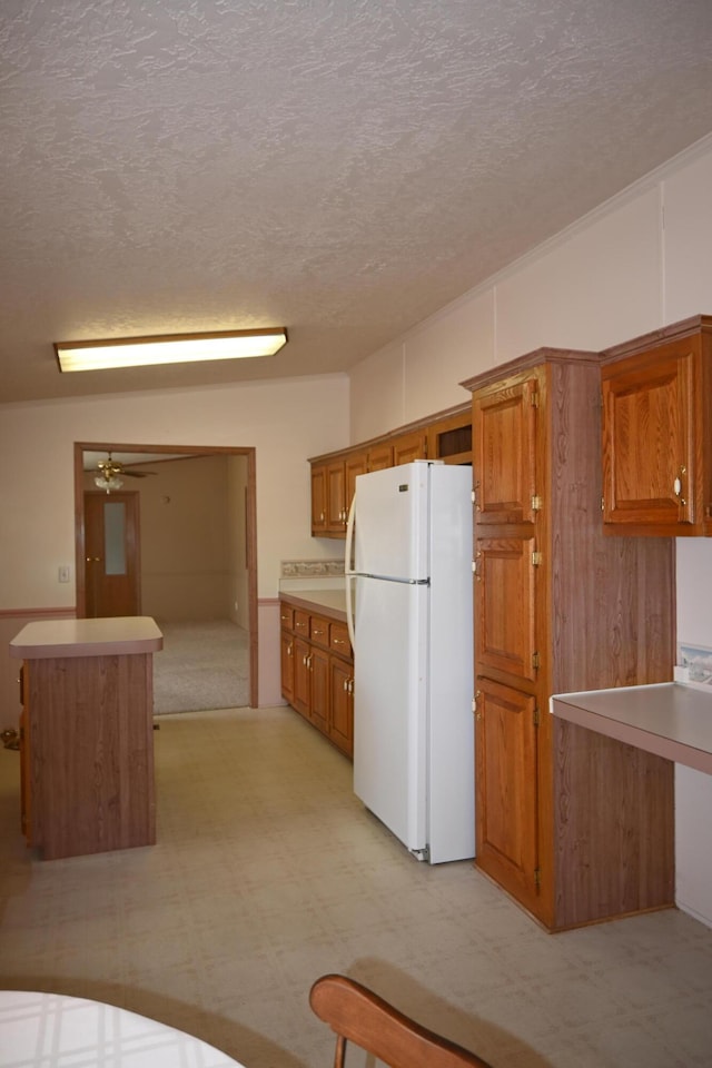 4105 Sawgrass Trl, Muskegon, MI 49442 - kitchen featuring freestanding refrigerator, brown cabinets, light flooring, a textured ceiling, and light countertops