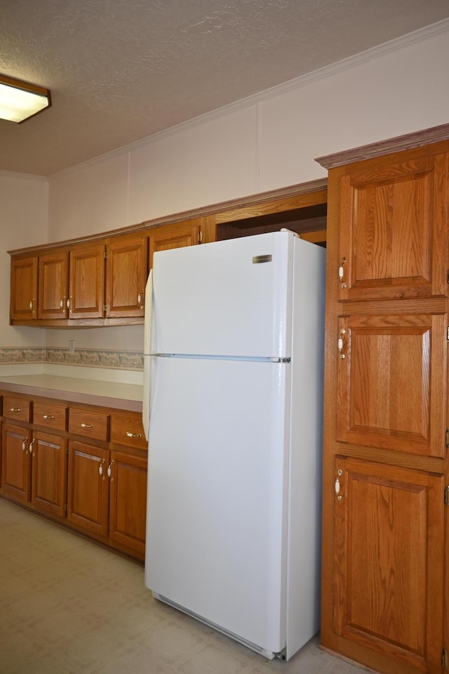 4105 Sawgrass Trl, Muskegon, MI 49442 - kitchen with freestanding refrigerator, brown cabinets, light countertops, a textured ceiling, and ornamental molding