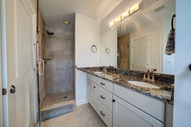982 Lake Ridge Dr, Traverse City, MI 49684 - bathroom featuring a tile shower, double vanity, and tile patterned floors