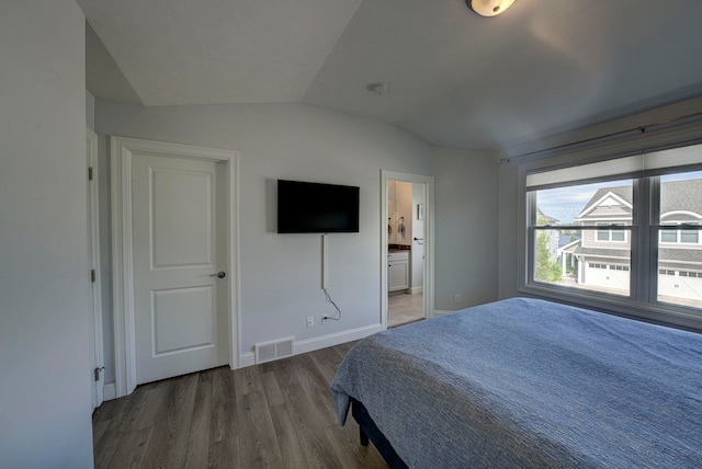 982 Lake Ridge Dr, Traverse City, MI 49684 - bedroom with lofted ceiling, wood finished floors, and ensuite bathroom
