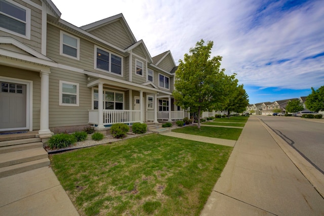 982 Lake Ridge Dr, Traverse City, MI 49684 - townhome / multi-family property with a porch, a front yard, and a residential view