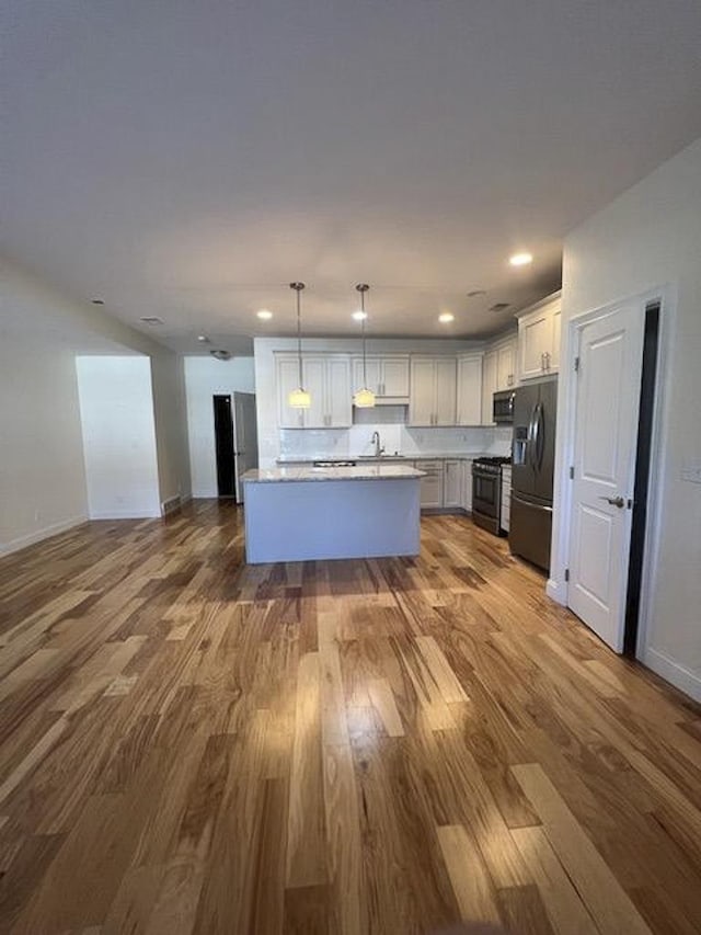 982 Lake Ridge Dr, Traverse City, MI 49684 - kitchen with appliances with stainless steel finishes, open floor plan, wood finished floors, hanging light fixtures, and recessed lighting