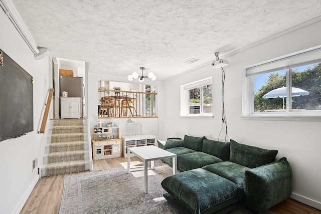 9241 Abbey Ln, Ypsilanti, MI 48198 - living area with light wood-type flooring, stairs, a textured ceiling, and a chandelier