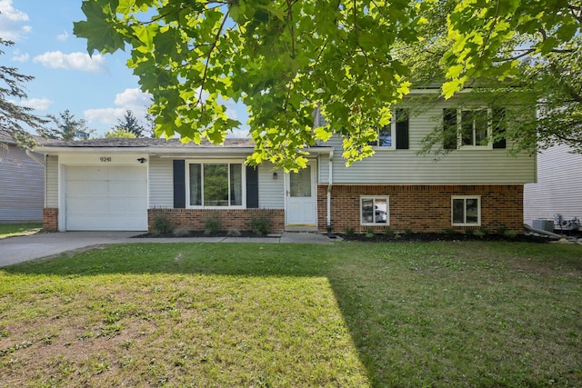 9241 Abbey Ln, Ypsilanti, MI 48198 - split level home with brick siding, a front yard, an attached garage, and driveway