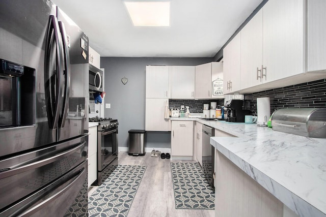 6779 1st Dr, Coloma, MI 49038 - kitchen featuring appliances with stainless steel finishes, light countertops, tasteful backsplash, light wood-style flooring, and white cabinetry