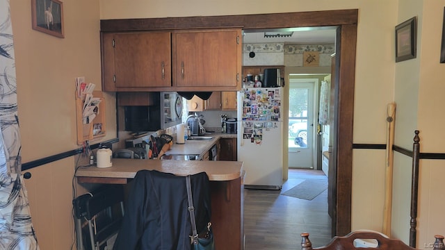511 E Main St, Morenci, MI 49256 - kitchen featuring freestanding refrigerator, stainless steel microwave, wood finished floors, light countertops, and brown cabinetry