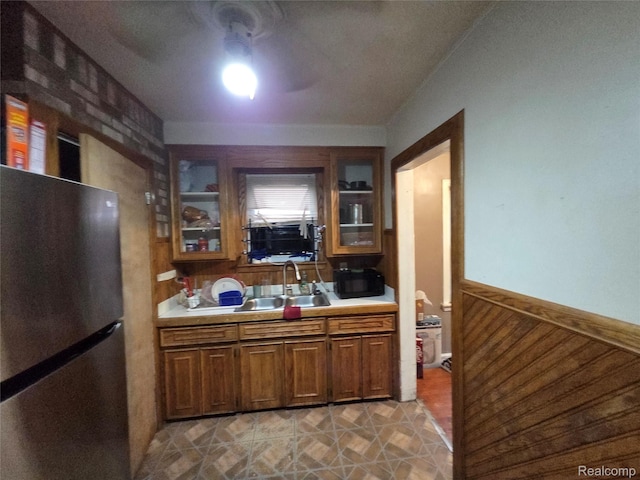 19466 Packard St, Detroit, MI 48234 - kitchen featuring freestanding refrigerator, light countertops, glass insert cabinets, wainscoting, and brown cabinetry