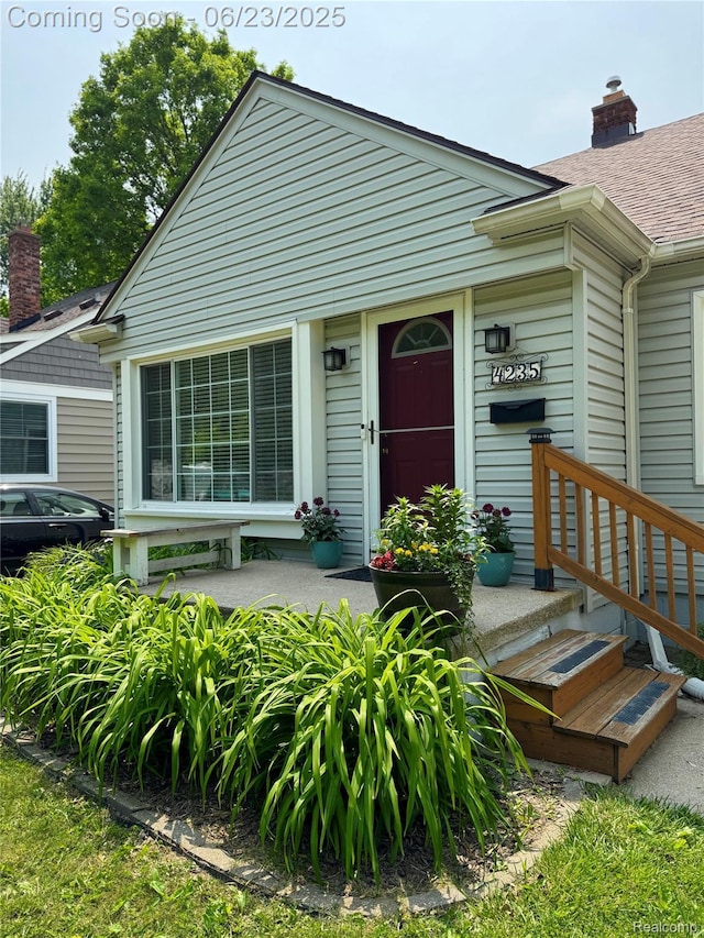 4235 Bacon Ave, Berkley, MI 48072 - view of exterior entry featuring roof with shingles and a chimney