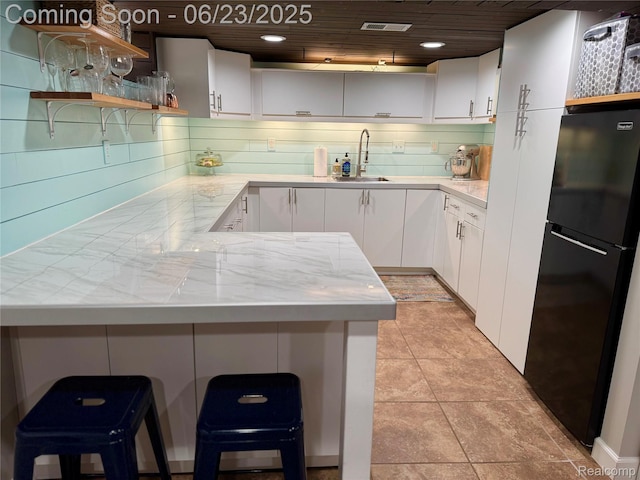 4235 Bacon Ave, Berkley, MI 48072 - kitchen featuring freestanding refrigerator, open shelves, white cabinets, a peninsula, and a breakfast bar