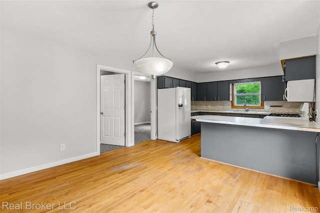 1059 Morris Hills Pkwy, Mount Morris, MI 48458 - kitchen featuring white appliances, a peninsula, light countertops, decorative backsplash, and light wood-style floors