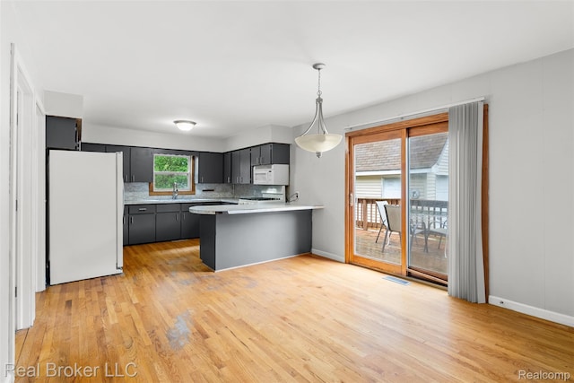 1059 Morris Hills Pkwy, Mount Morris, MI 48458 - kitchen featuring white appliances, a peninsula, tasteful backsplash, light wood-type flooring, and light countertops