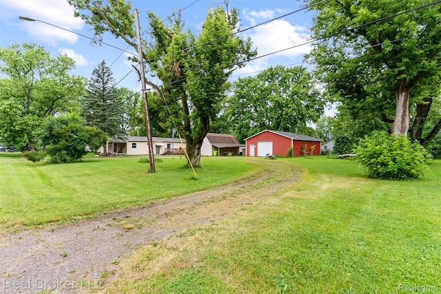 1059 Morris Hills Pkwy, Mount Morris, MI 48458 - view of green lawn featuring driveway, a detached garage, and an outdoor structure